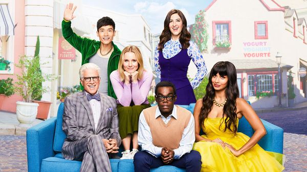 The cast of the TV show The Good Place are seated on a couch in the town square of the afterlife.