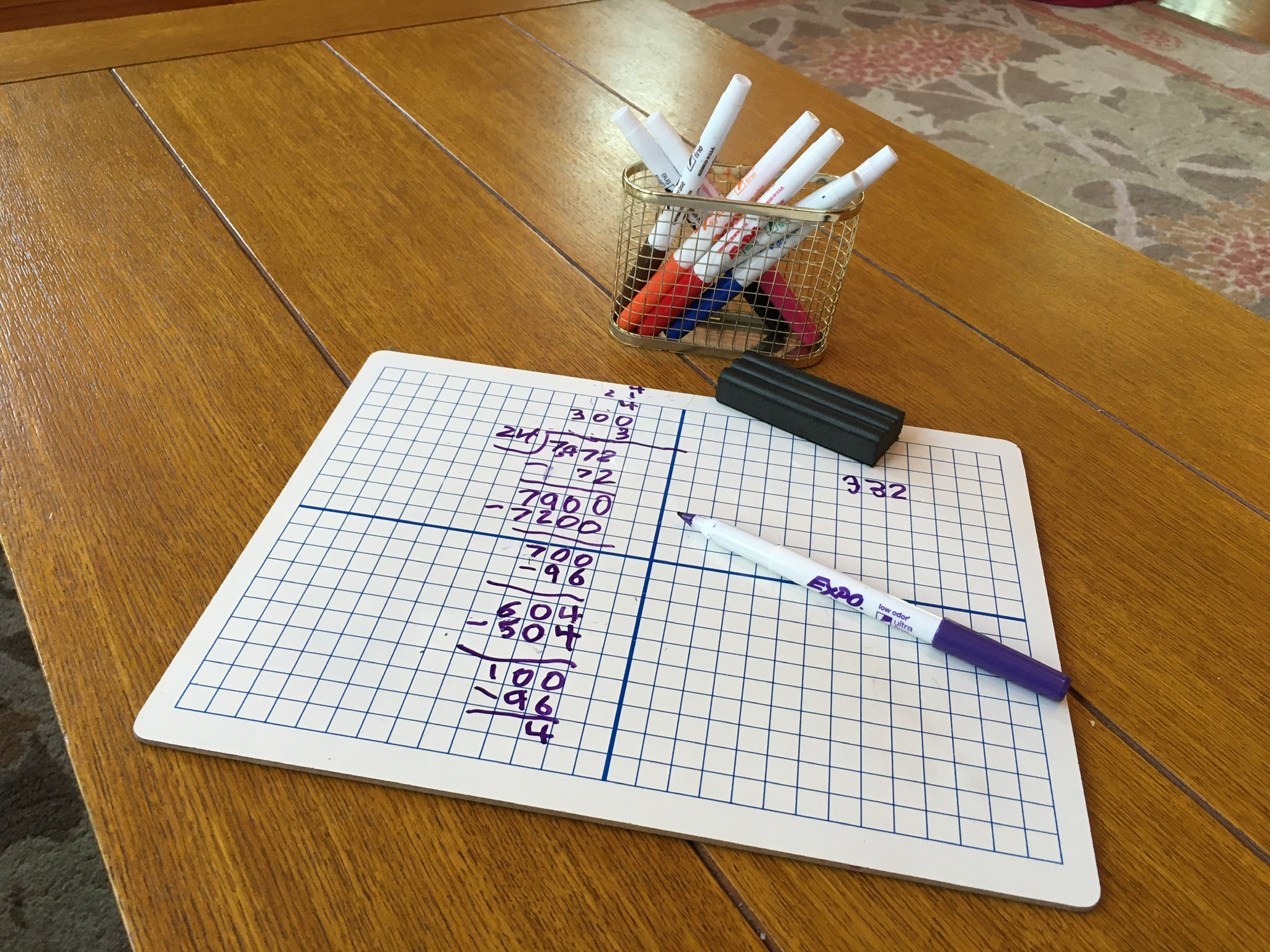 A small whiteboard, marked with grid lines, and a long division math problem written on it.