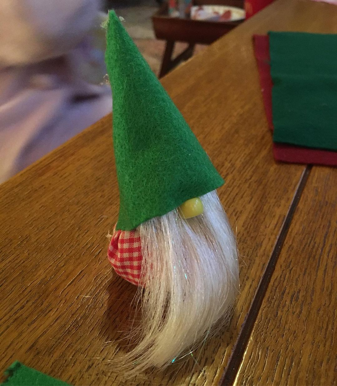 A small homemade gnome-like doll, with a pointed green hat and a white beard.