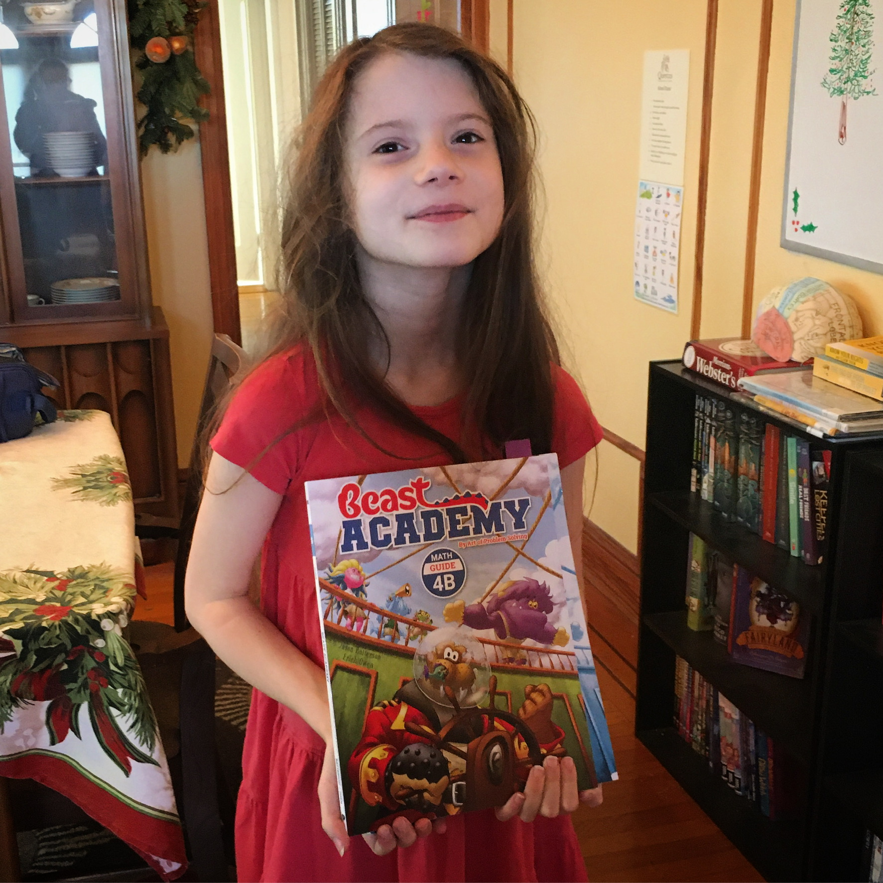 Wanda, an 8-year-old girl, holding the colorful math book Beast Academy 4B.