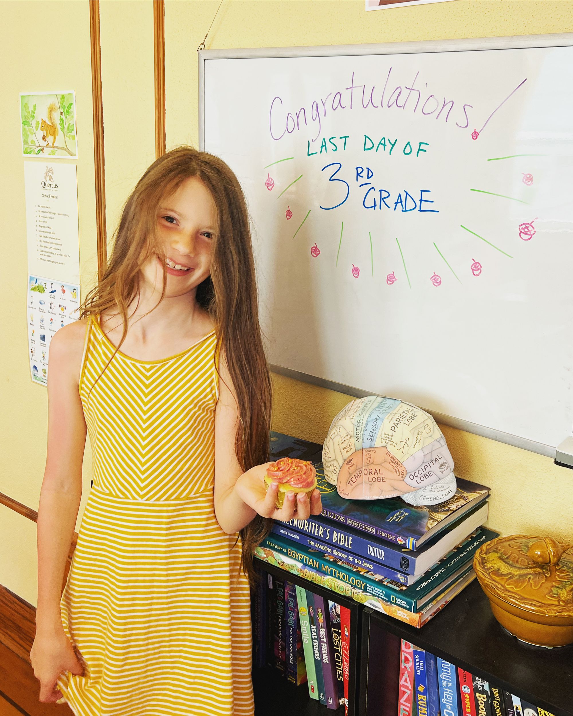 Wanda, wearing a yellow-and-white striped sundress, holding a pink cupcake. The whiteboard says, "Congratulations! Last day of 3rd grade!"