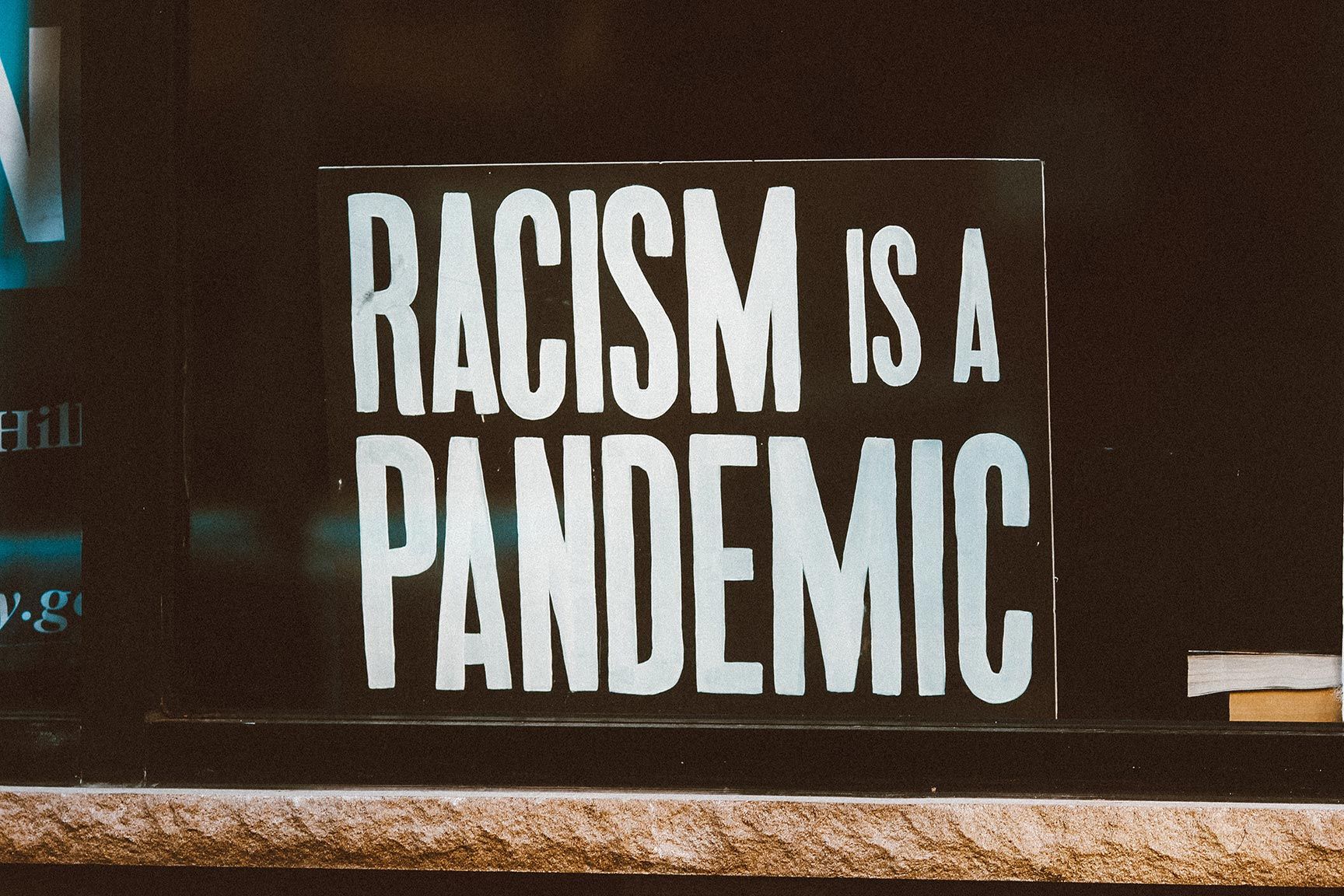 A sign reading "RACISM IS A PANDEMIC"