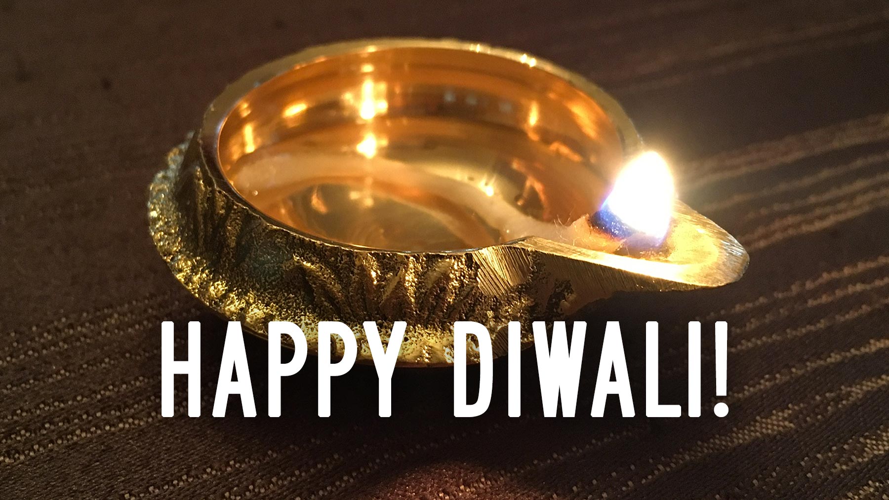 A lit diya (a small ceremonial oil lamp), with the words "Happy Diwali!"