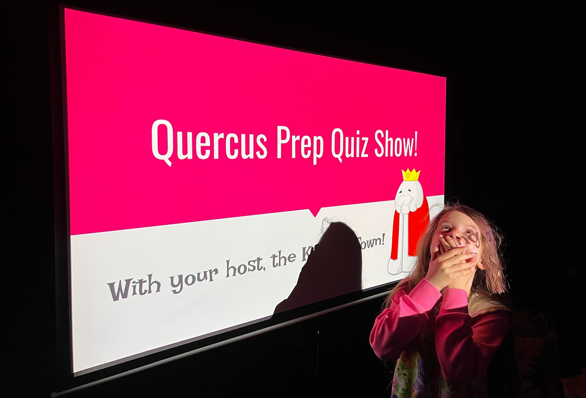 Wanda has her hands clasped over her joyfully agape mouth, in front of the Quiz Show intro slide.
