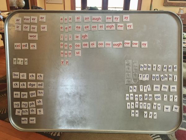 Tiles with letters and letter groups (phonograms), arranged on a metal tray. 