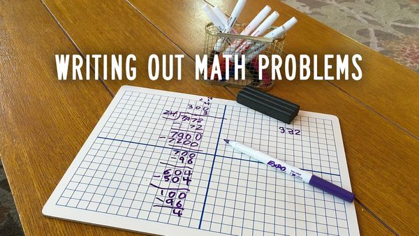 A small whiteboard, marked with grid lines, and a long division math problem written on it.