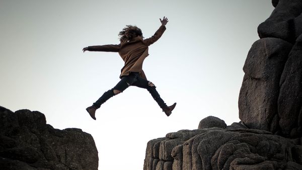 A young woman leaps over a chasm