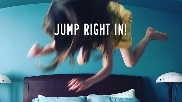 A young girl in a yellow dress is hovering in midair over a bed, her hair flying. Overlaid text in white: JUMP ON IN!