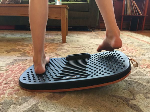 Wanda's feet and lower legs are seen standing on a curved wooden board, with a nubbly black cushion top.